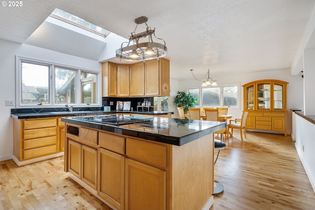 kitchen featuring light wood-style floors, dark countertops, cooktop, and a kitchen island