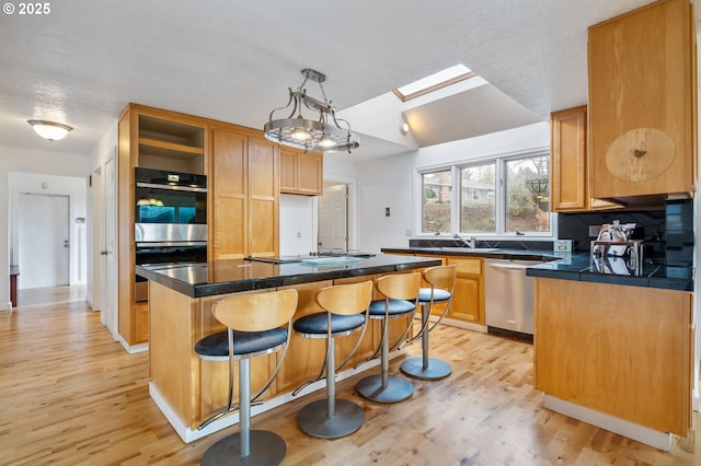 kitchen featuring light wood finished floors, open shelves, appliances with stainless steel finishes, and a breakfast bar area