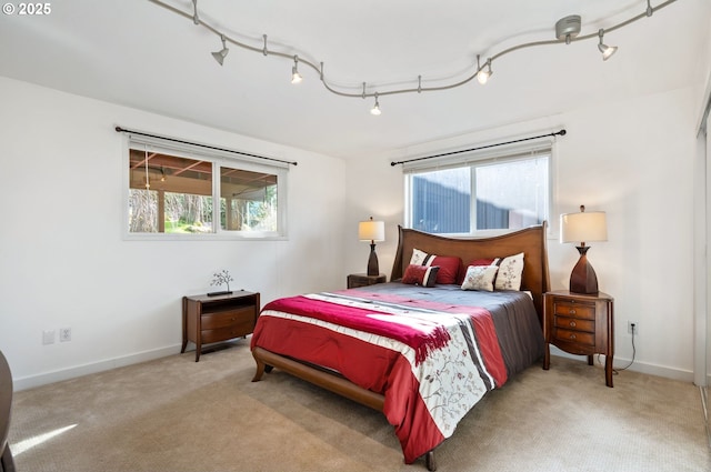 carpeted bedroom featuring track lighting, multiple windows, and baseboards