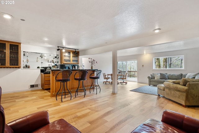 interior space with light wood-style floors, baseboards, wet bar, and visible vents