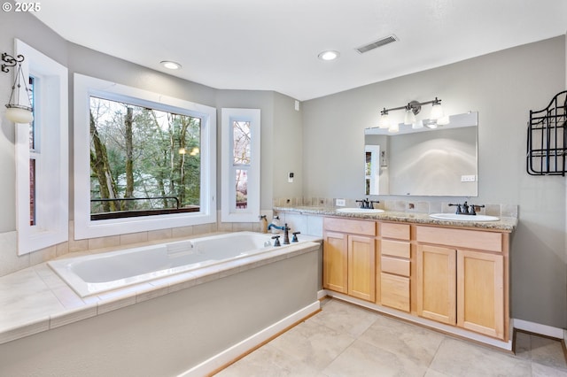 full bath with double vanity, a garden tub, visible vents, and a sink