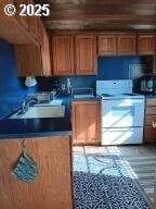25 Fraser Rd, Tillamook, OR 97141 - kitchen with white range with electric stovetop, a sink, brown cabinetry, and wood finished floors