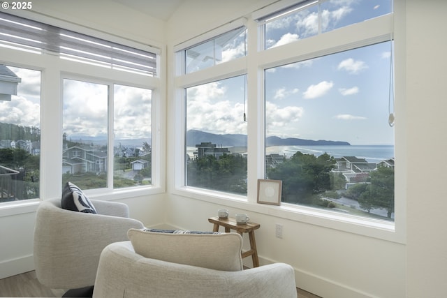sunroom with wood finished floors, baseboards, a mountain view, and a healthy amount of sunlight