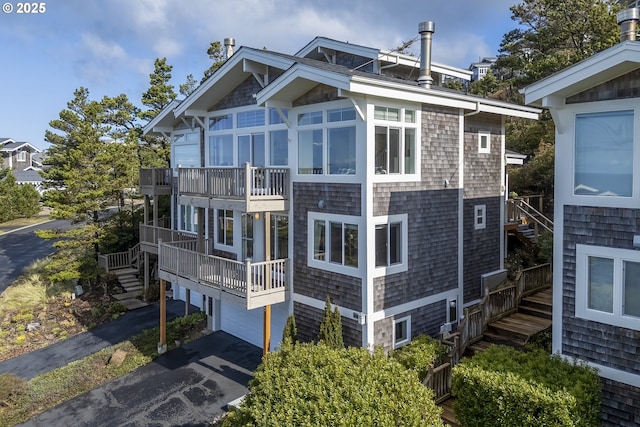 view of property featuring aphalt driveway, stairs, and an attached garage
