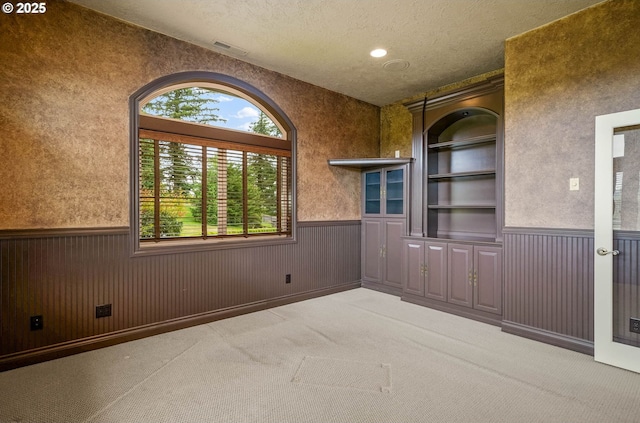 12033 S Shadow Hills Ct, Turner, OR 97392 - unfurnished room featuring wainscoting, a textured ceiling, carpet flooring, built in shelves, and wood walls