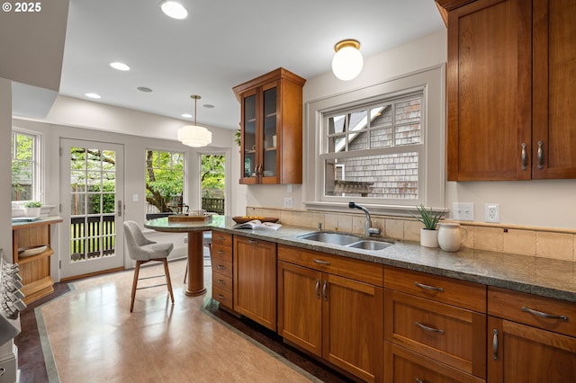 2815 NE 35th Ave, Portland, OR 97212 - kitchen with a sink, brown cabinets, glass insert cabinets, dark stone countertops, and pendant lighting