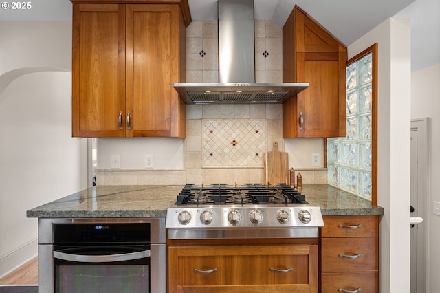 2815 NE 35th Ave, Portland, OR 97212 - kitchen with wall chimney range hood, stainless steel gas cooktop, wall oven, brown cabinets, and tasteful backsplash