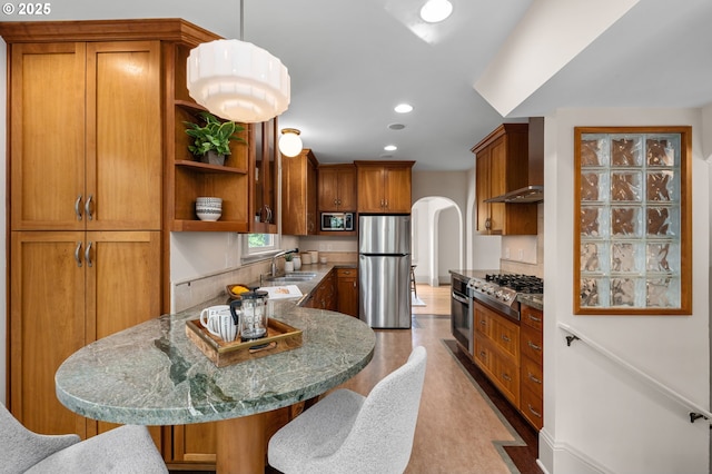 2815 NE 35th Ave, Portland, OR 97212 - kitchen with stainless steel appliances, wall chimney exhaust hood, a sink, arched walkways, and brown cabinetry