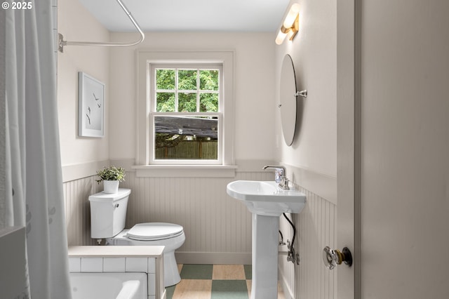2815 NE 35th Ave, Portland, OR 97212 - bathroom with a wainscoted wall, toilet, a bathtub, a shower with curtain, and a sink