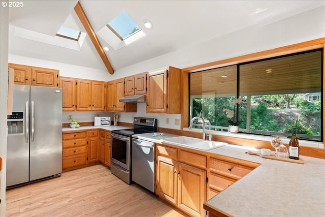 115 Willow St, Silverton, OR 97381 - kitchen with appliances with stainless steel finishes, under cabinet range hood, a skylight, light countertops, and light wood-type flooring