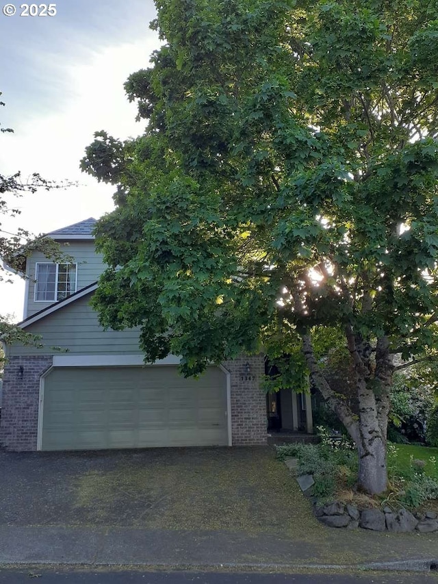 1347 NE Paloma Ave, Gresham, OR 97030 - view of property hidden behind natural elements with brick siding, an attached garage, and asphalt driveway