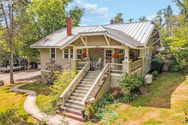 view of front of house featuring a standing seam roof, a chimney, stairs, a front lawn, and metal roof