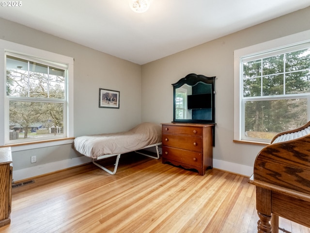 bedroom featuring baseboards, multiple windows, visible vents, and light wood finished floors