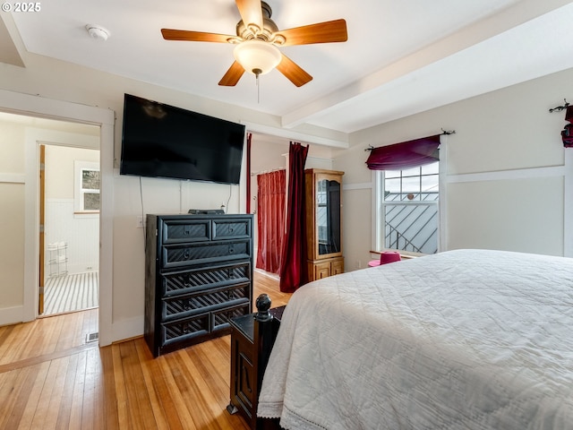 bedroom with light wood finished floors, beamed ceiling, and ceiling fan