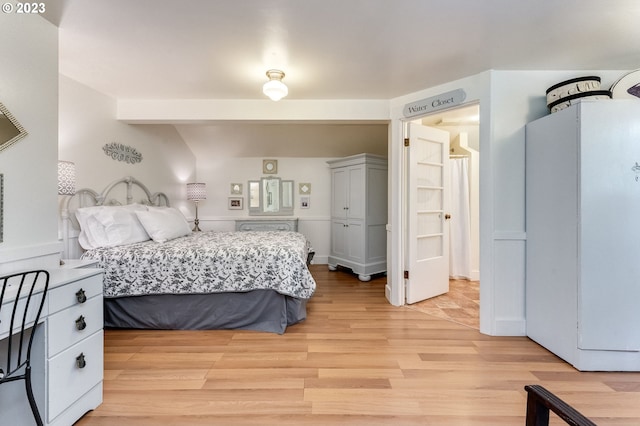 bedroom featuring light wood-style flooring and freestanding refrigerator