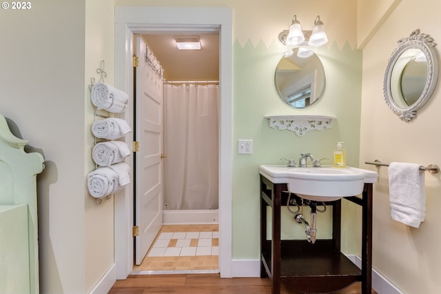 full bath featuring curtained shower, wood finished floors, and baseboards