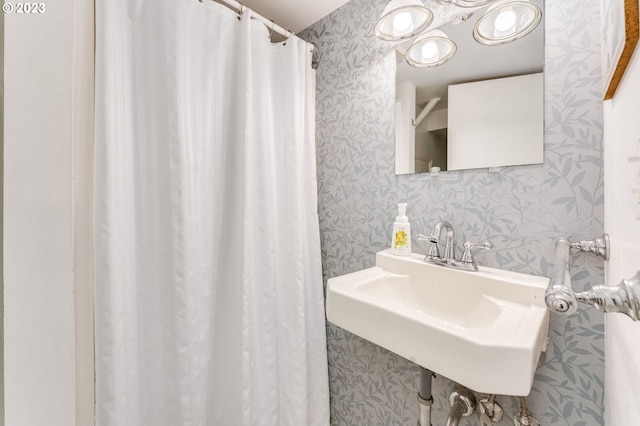 full bathroom with wallpapered walls and a sink