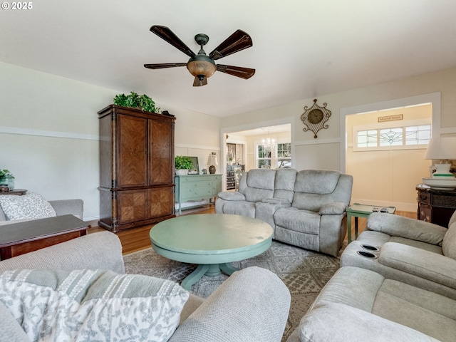 living area with ceiling fan with notable chandelier and wood finished floors