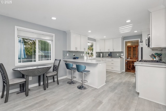 5355 SW 205th Ct, Beaverton, OR 97078 - kitchen featuring refrigerator, decorative backsplash, white cabinets, light countertops, and a peninsula