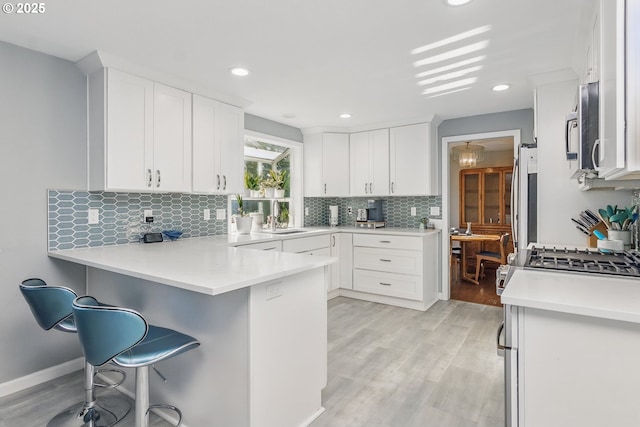 5355 SW 205th Ct, Beaverton, OR 97078 - kitchen featuring a peninsula, a breakfast bar area, white cabinetry, light wood-style flooring, and stainless steel appliances