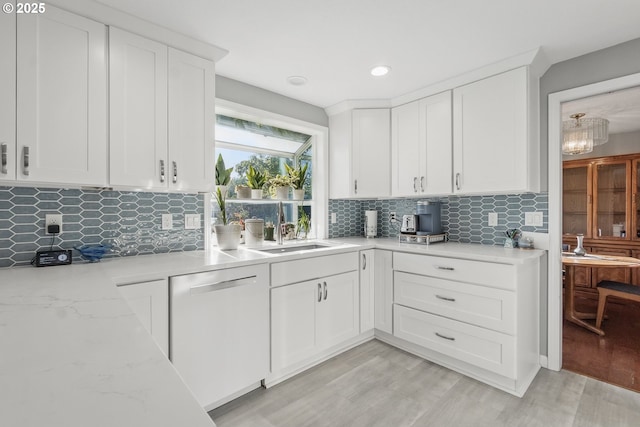 5355 SW 205th Ct, Beaverton, OR 97078 - kitchen with dishwashing machine, a sink, white cabinetry, decorative backsplash, and light wood-style floors