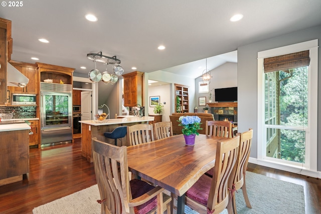 dining room with recessed lighting, lofted ceiling, dark wood finished floors, and a fireplace