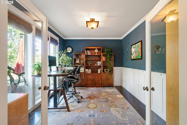 home office with crown molding, a wainscoted wall, wood finished floors, and french doors