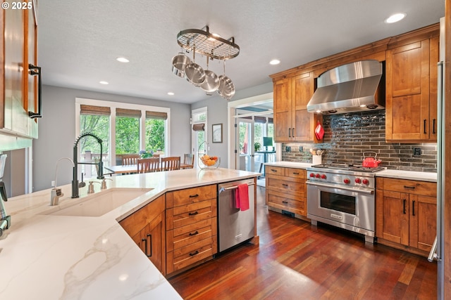 kitchen featuring wall chimney exhaust hood, appliances with stainless steel finishes, recessed lighting, dark wood-style floors, and decorative backsplash