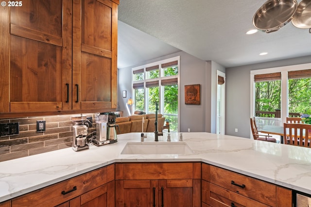 kitchen with a sink, plenty of natural light, tasteful backsplash, brown cabinets, and recessed lighting