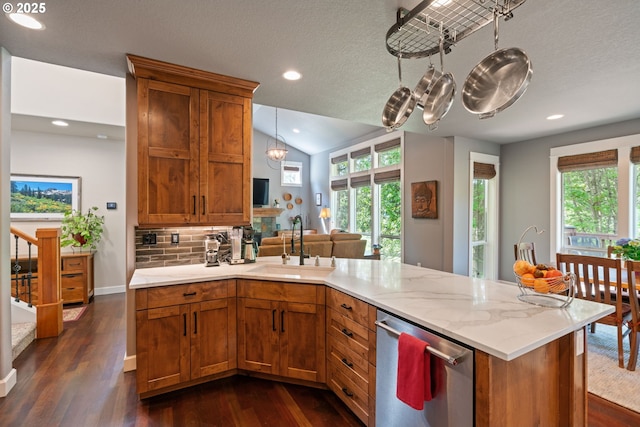kitchen with stainless steel dishwasher, a sink, brown cabinets, dark wood-style flooring, and a peninsula