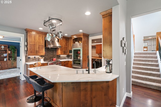 kitchen featuring appliances with stainless steel finishes, washing machine and dryer, extractor fan, dark wood-style floors, and backsplash