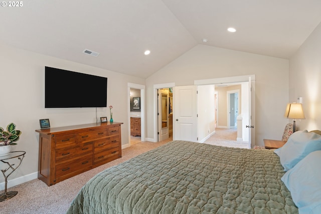 bedroom featuring lofted ceiling, light colored carpet, baseboards, a walk in closet, and ensuite bathroom