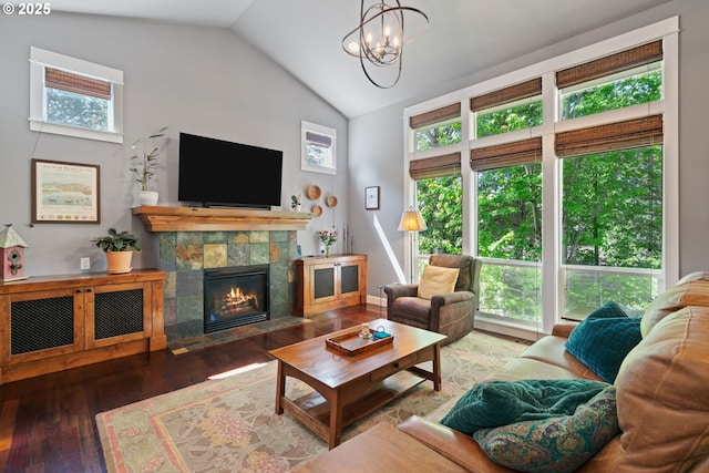 living room featuring vaulted ceiling, wood finished floors, a fireplace, and a chandelier