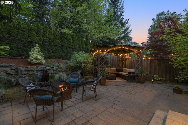 patio terrace at dusk featuring a fenced backyard, an outdoor living space with a fire pit, and a pergola
