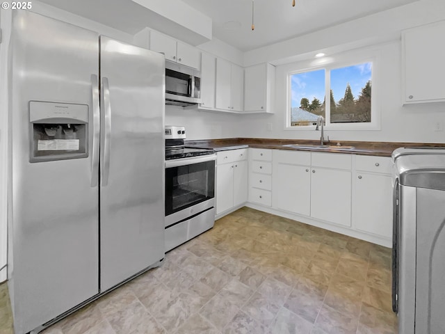 kitchen with a sink, dark countertops, washer / clothes dryer, and stainless steel appliances