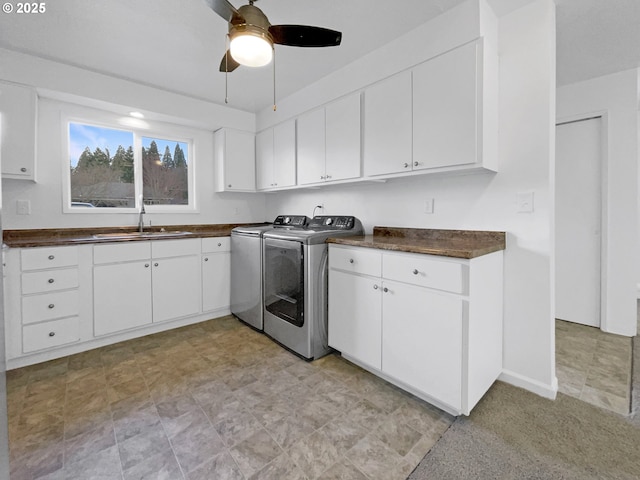 laundry area featuring baseboards, cabinet space, ceiling fan, a sink, and washer and clothes dryer