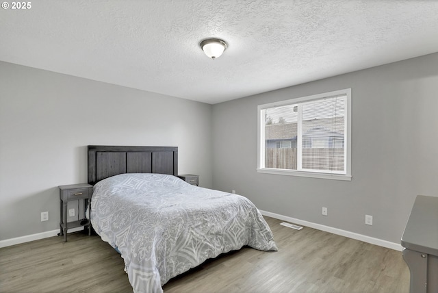 bedroom with wood-type flooring and a textured ceiling