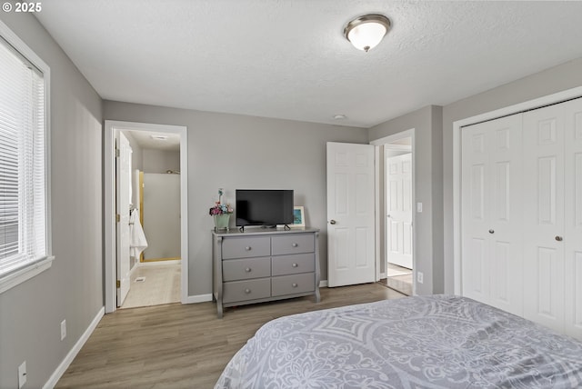 bedroom featuring a closet, ensuite bathroom, a textured ceiling, and light hardwood / wood-style flooring