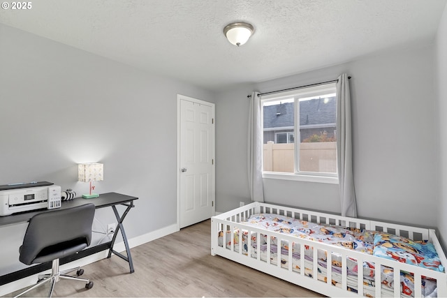 bedroom with light hardwood / wood-style floors and a textured ceiling