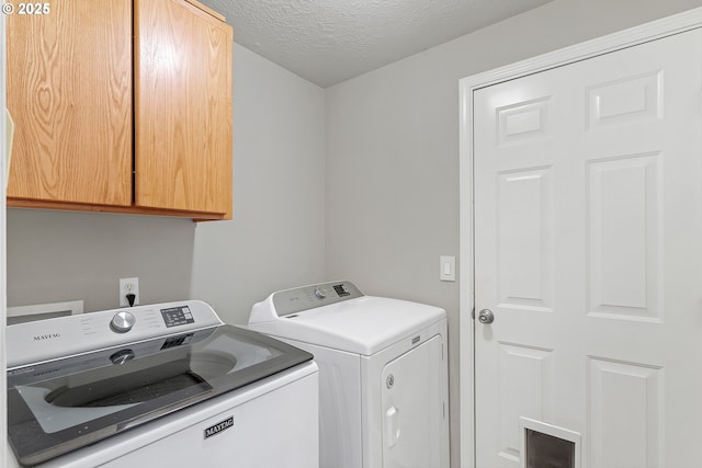 laundry area featuring washing machine and dryer, cabinets, and a textured ceiling