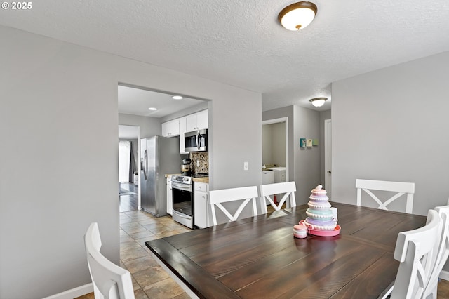 tiled dining area with washer and dryer and a textured ceiling