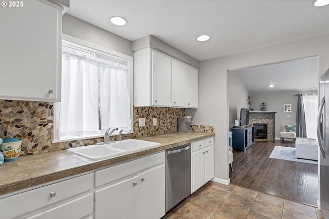 kitchen featuring stainless steel appliances, sink, white cabinets, and a fireplace