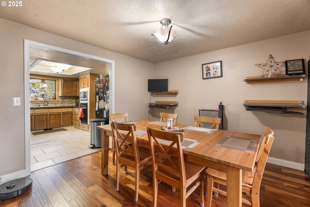 dining area featuring a textured ceiling, wood-type flooring, and sink