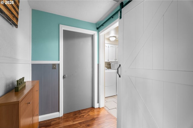 hallway featuring washer and dryer, a barn door, and hardwood / wood-style floors