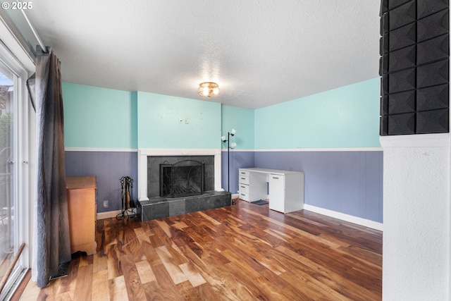 unfurnished living room with a tile fireplace, a textured ceiling, and hardwood / wood-style flooring