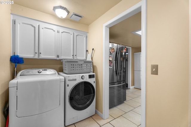 laundry area featuring separate washer and dryer, cabinets, and light tile patterned floors