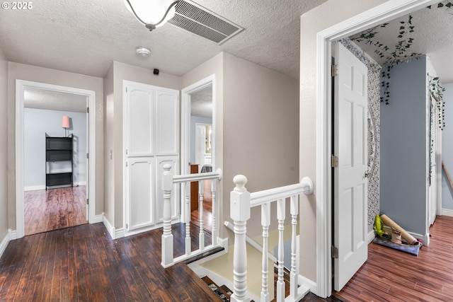 hall with dark wood-type flooring and a textured ceiling