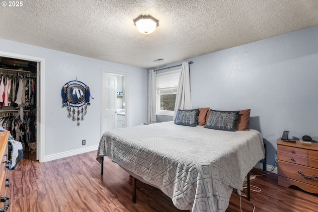 bedroom featuring a walk in closet, ensuite bath, a closet, and hardwood / wood-style flooring