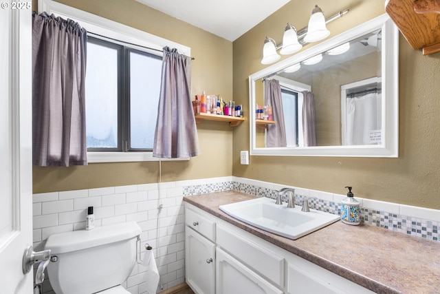 bathroom featuring toilet, vanity, and tile walls