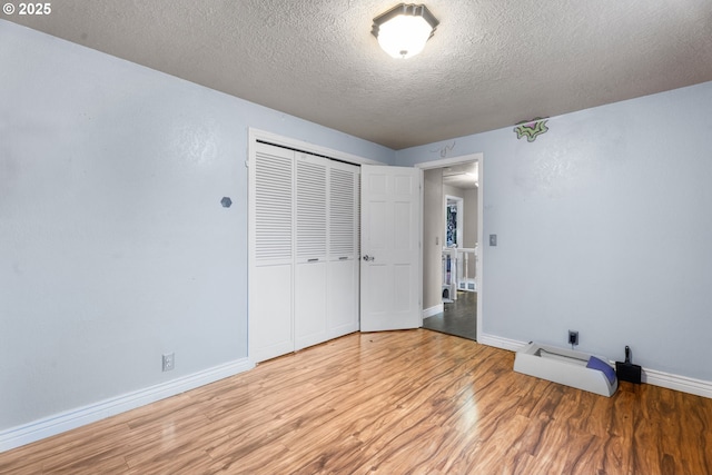 unfurnished bedroom with a textured ceiling, a closet, and light hardwood / wood-style flooring